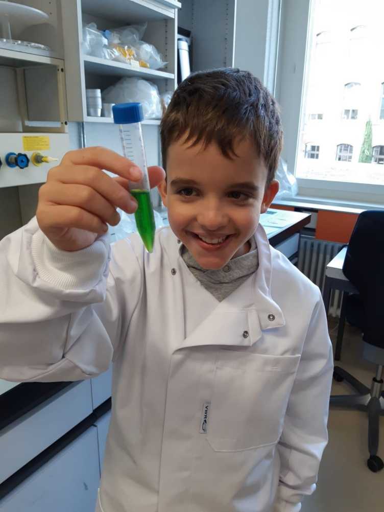 Smiling boy holding tube containing green liquid